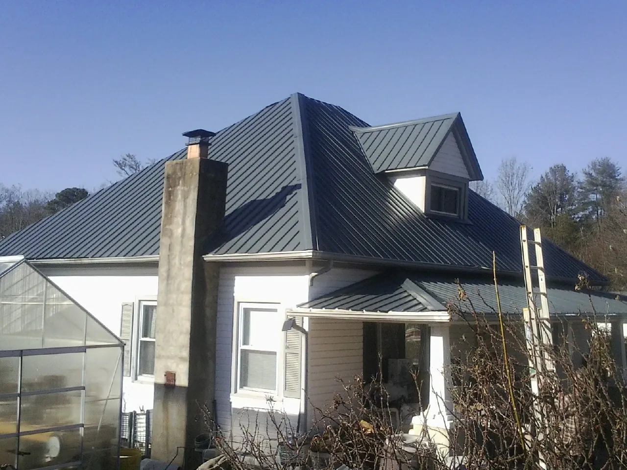 Dark blue standing seam metal roof on a white farmhouse with dormer — Slate & Tile Roof Repair by Roofing Brothers in Mammoth Cave