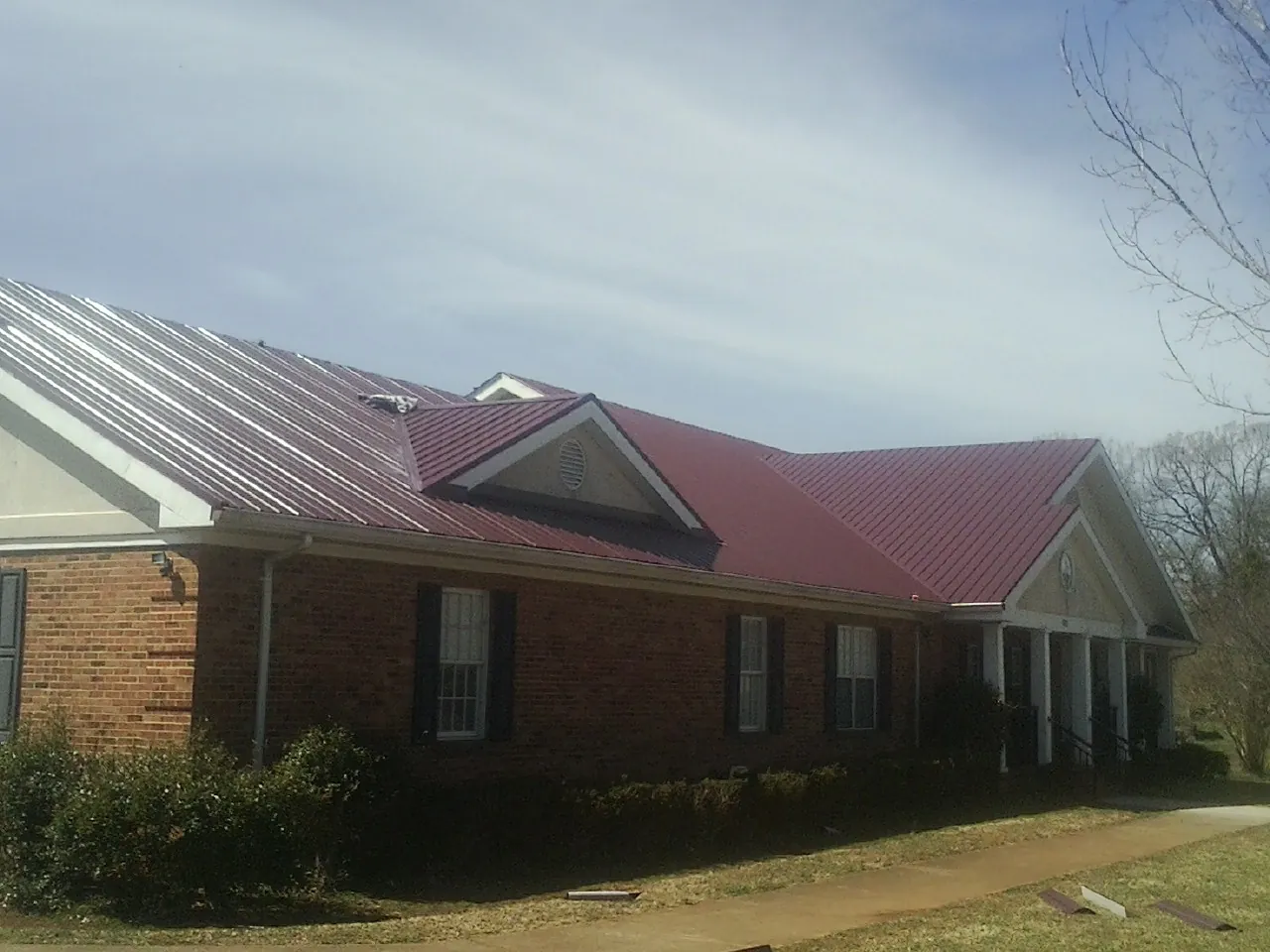 Red metal roof with gabled entries on a long brick building, from a Hail Damage Roof Repair job in Mammoth Cave