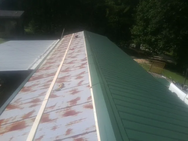 Old rusted panels beside newly installed green metal roofing — Wind Damage Roof Repair by Roofing Brothers in Mammoth Cave