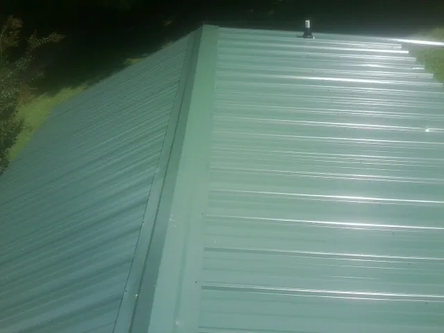 New green metal panels meeting at the ridge of a roof — Flat Roof Repair work by our crew in Mammoth Cave