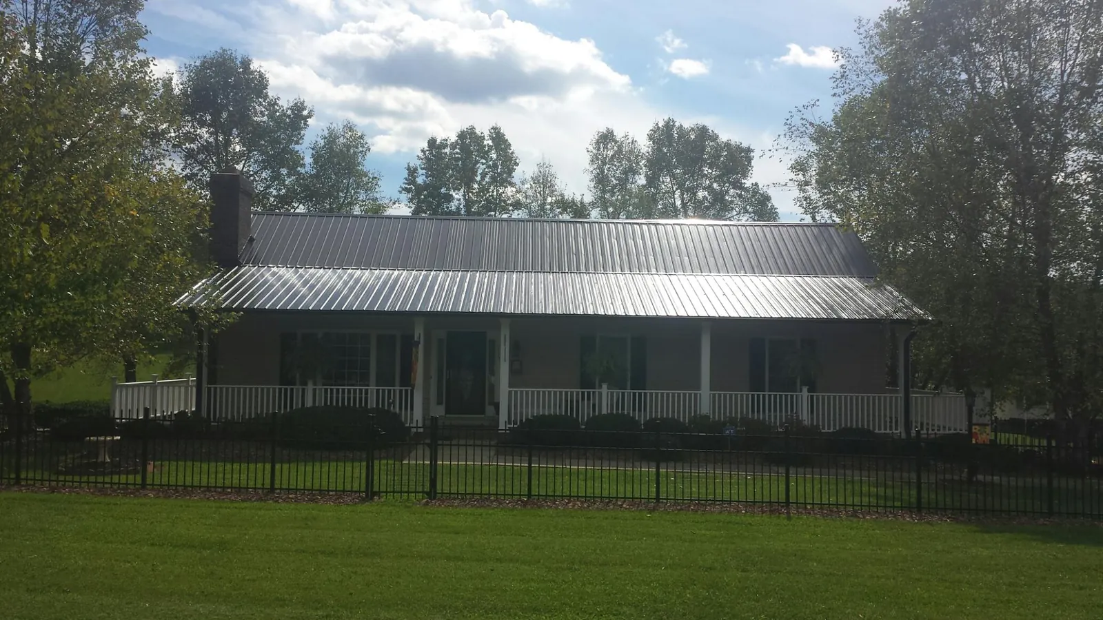 Gray metal roof on a brick ranch with a full width front porch — Gutter Guard Installation work by our crew in Mammoth Cave