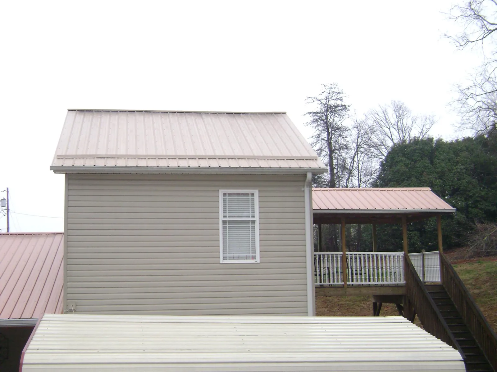 Tan metal roofs on a two story addition and attached porch, from a Roof Replacement job in Mammoth Cave