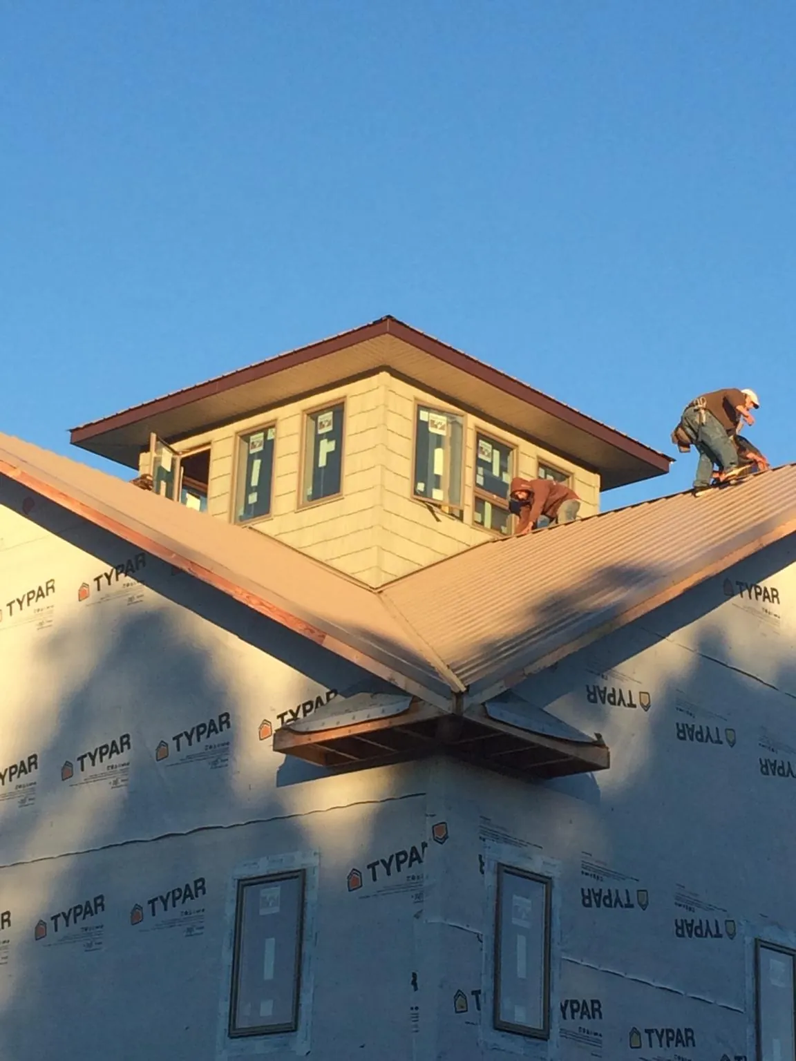 Roofers working around a rooftop cupola on a new metal roof at sunset — Roof Waterproofing in Mammoth Cave by Roofing Brothers